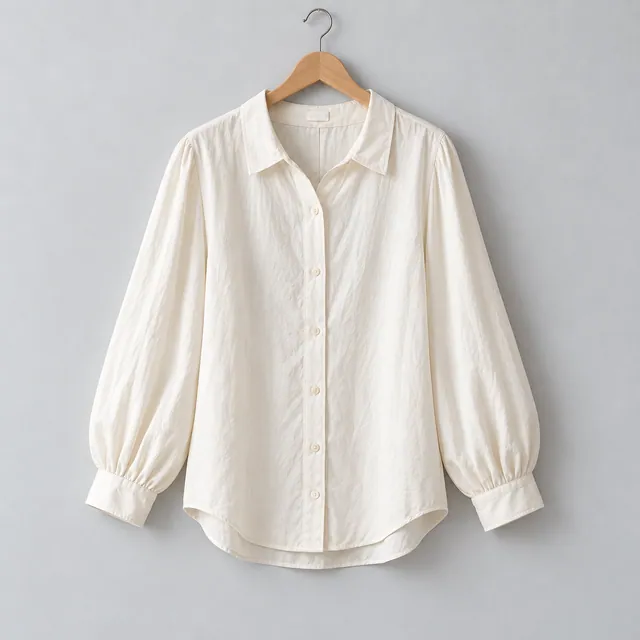 Blusa Lía marfil de cuello clásico y mangas largas, en una percha